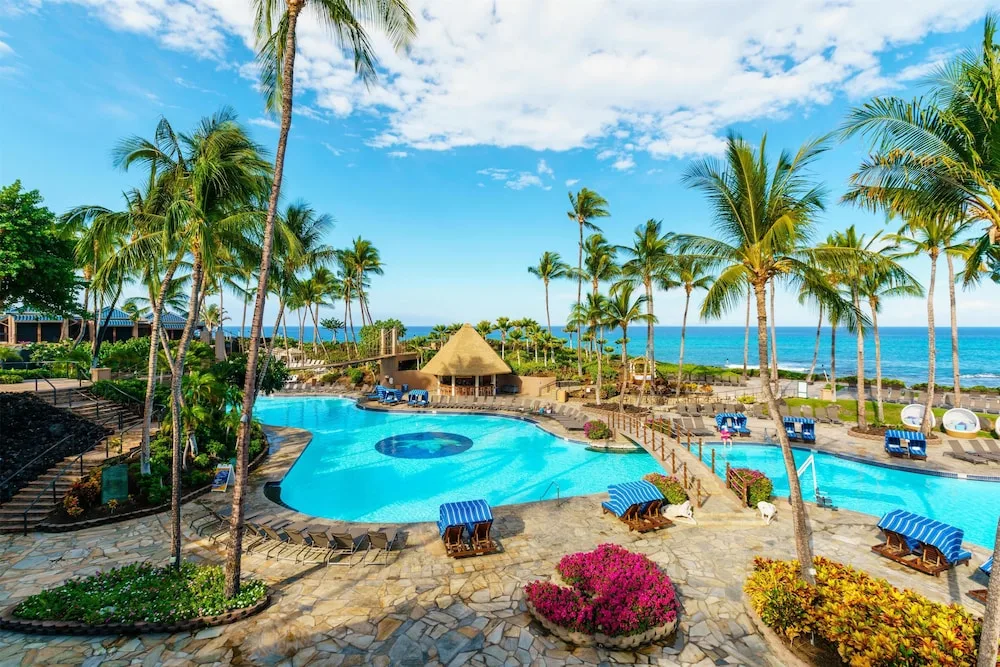 Oceanfront pool with palms and lounge chairs at Hilton Waikoloa Village.