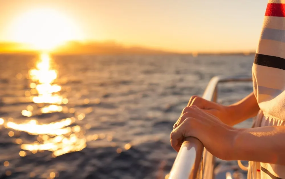 Guest hands on a boat rail at sunset near Hilton Waikoloa Village.