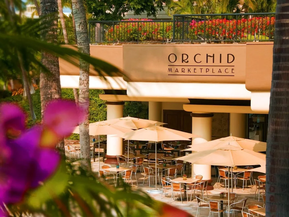 Orchid Marketplace patio with umbrellas and seating at Hilton Waikoloa Village.