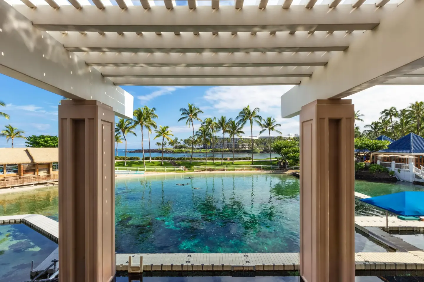Covered balcony view of lagoon, palms, and ocean at Hilton Waikoloa Village.