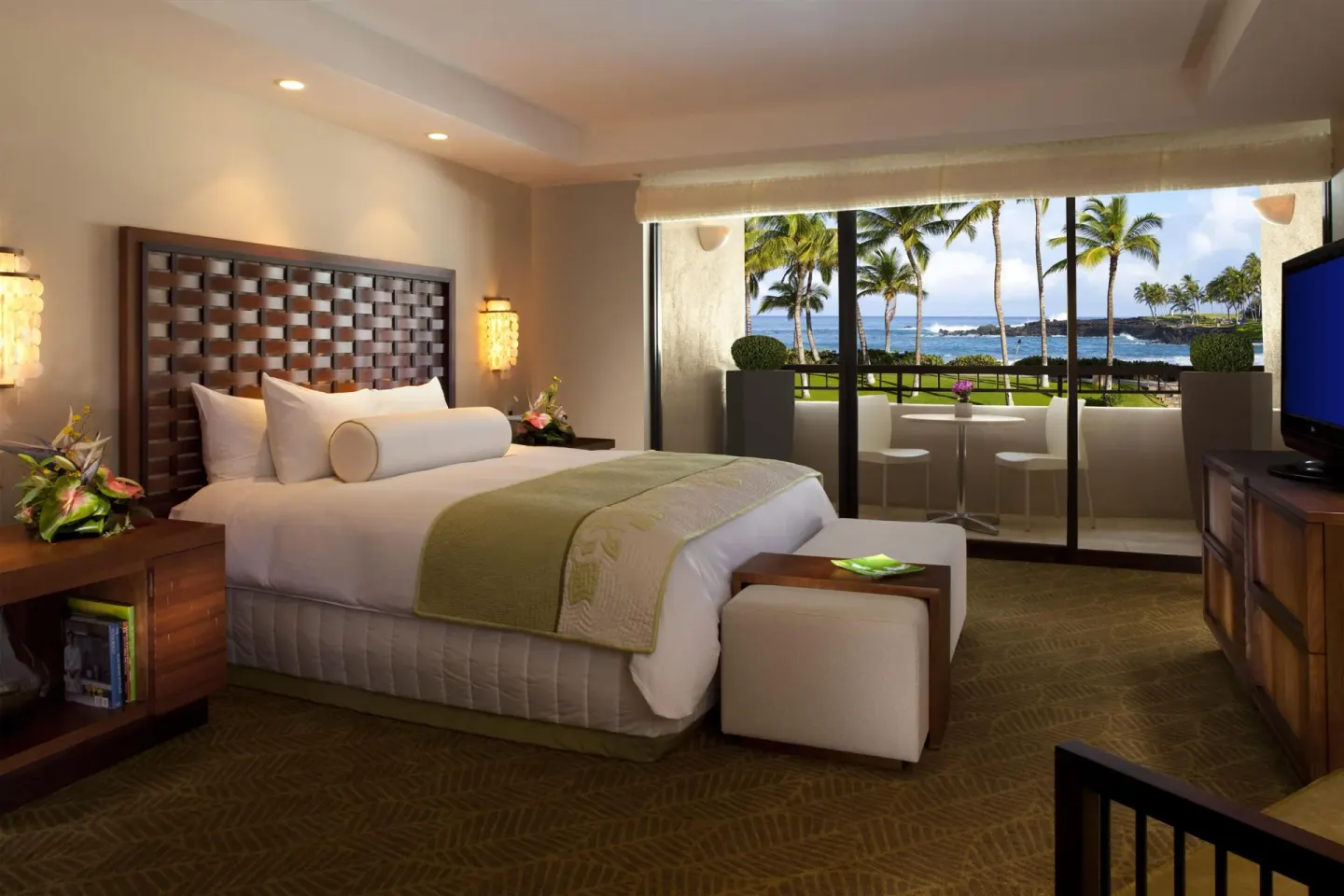 Bedroom with a large bed, TV, and ocean-view balcony at Hilton Waikoloa Village.