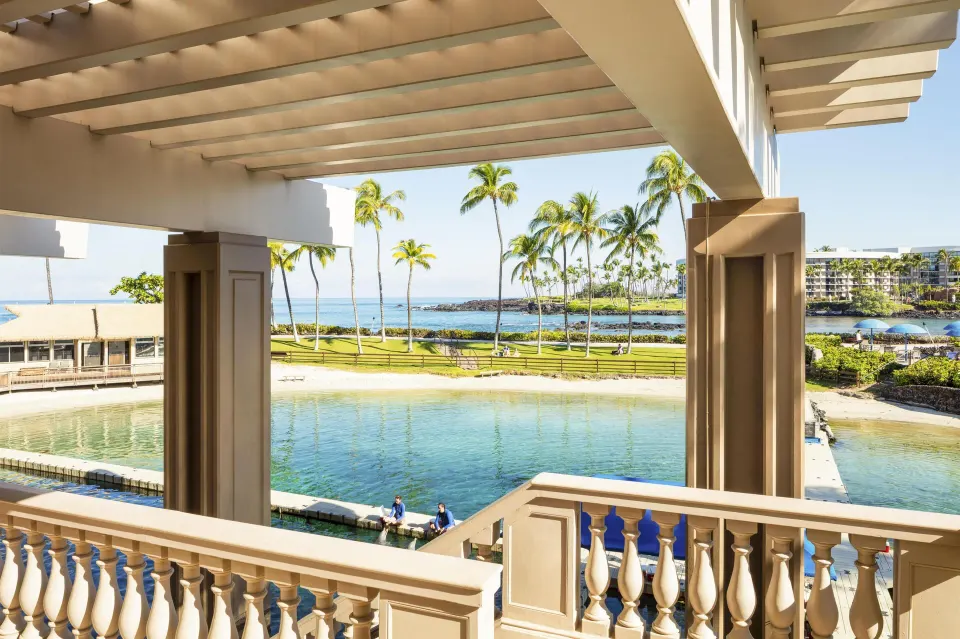 Covered lanai overlooks the lagoon, palms, and ocean at Hilton Waikoloa Village.
