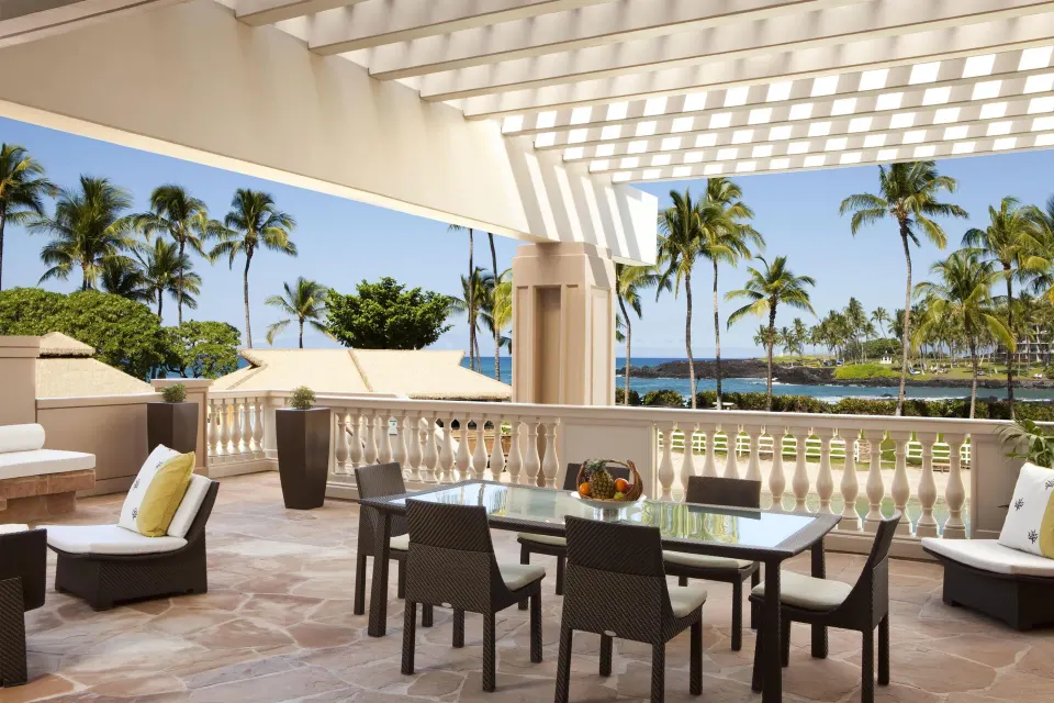 Spacious suite terrace with dining table and ocean views at Hilton Waikoloa Village.
