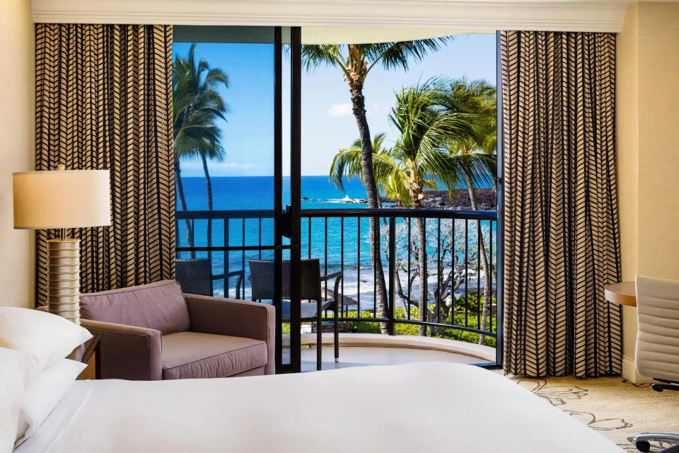Makai oceanfront room with bed, sofa, balcony, and ocean view at Hilton Waikoloa Village.