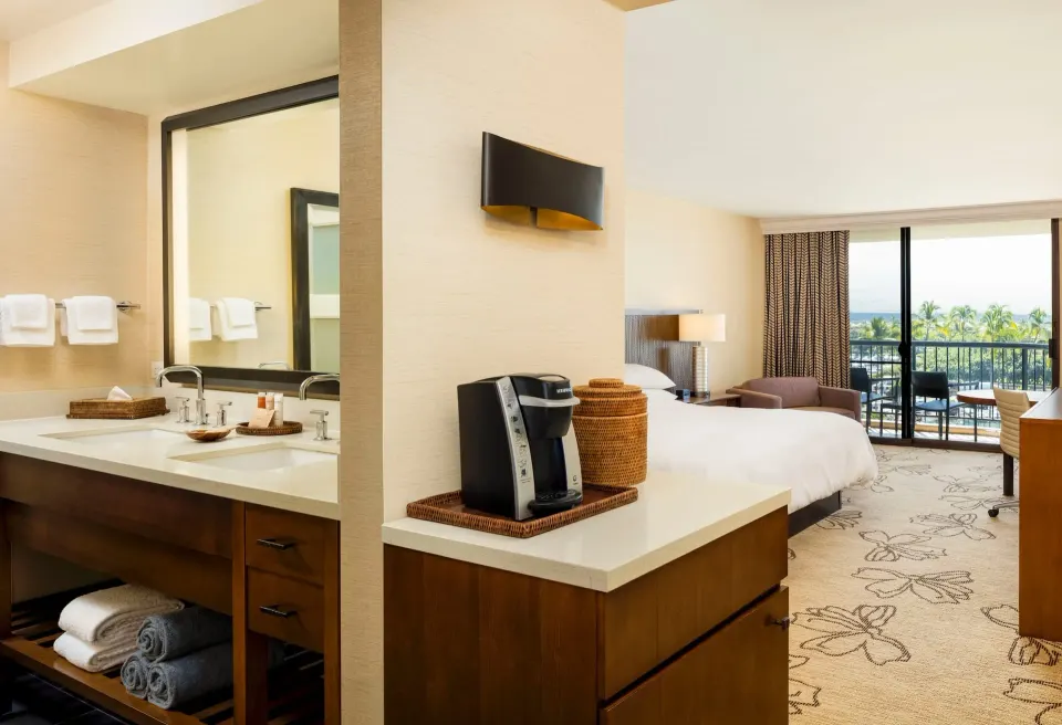 Resort view guest room with king bed, vanity, and balcony at Hilton Waikoloa Village.
