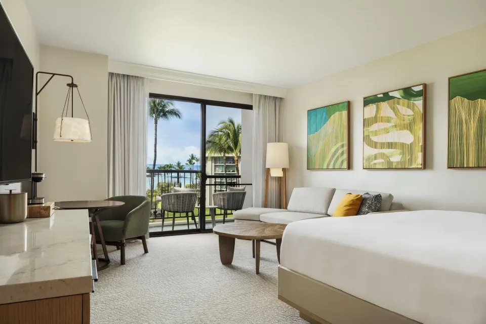 Ocean view guest room with king bed, sofa bed, desk, and balcony at Hilton Waikoloa Village.