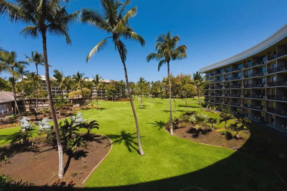 Resort view with palm lawn and guest room balconies at Hilton Waikoloa Village.