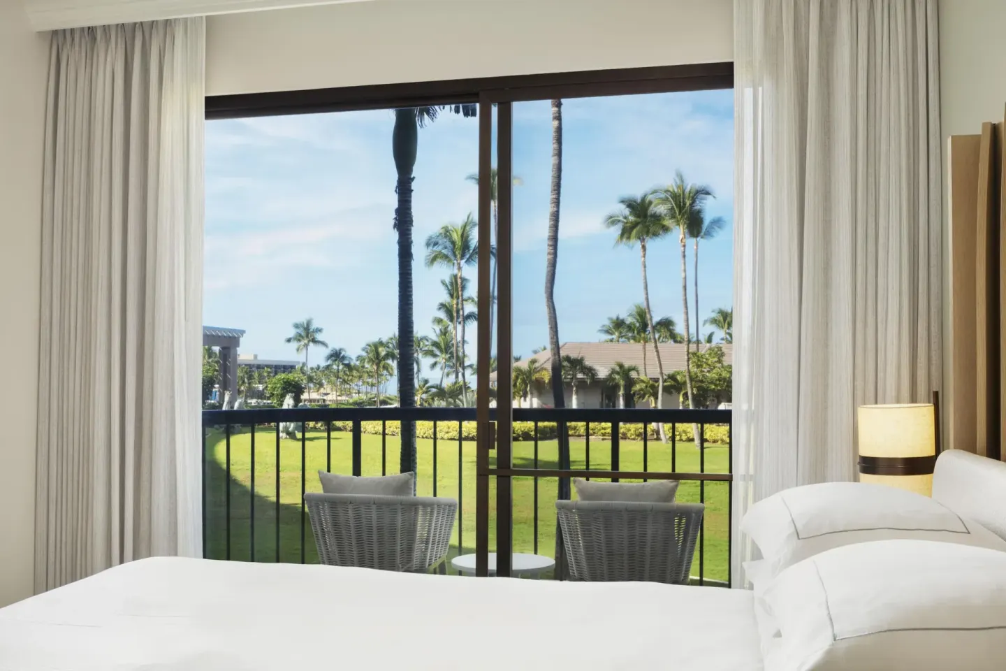 Resort view guest room bed and balcony at Hilton Waikoloa Village.