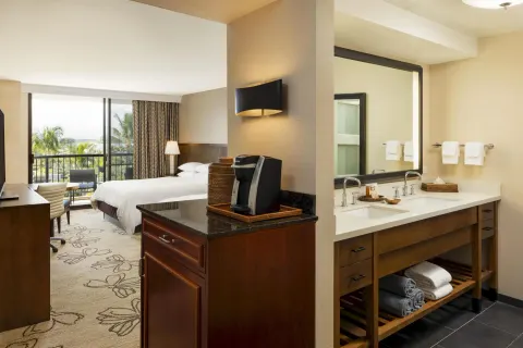 Accessible resort view room with bed, vanity, and coffee station at Hilton Waikoloa Village.