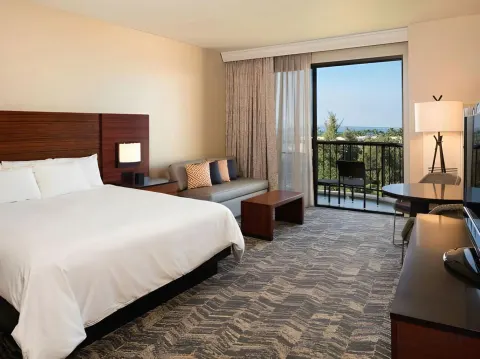 Ocean View Palace king room with sofa, desk, and balcony at Hilton Waikoloa Village.