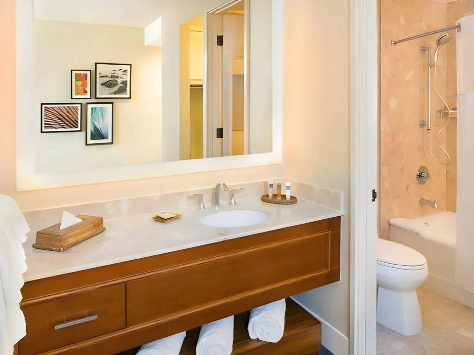 Bathroom vanity with lit mirror and shower area at Hilton Waikoloa Village.