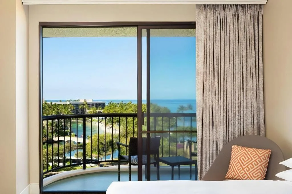 Ocean-view guest room balcony and bed at Hilton Waikoloa Village