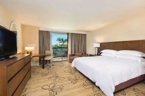 Ocean view king room with balcony, desk, TV, and seating at Hilton Waikoloa Village.
