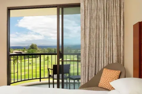 Resort view room balcony with bed and lounge chair at Hilton Waikoloa Village.