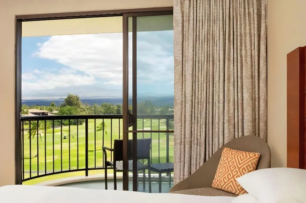 Resort view room balcony with bed and lounge chair at Hilton Waikoloa Village.