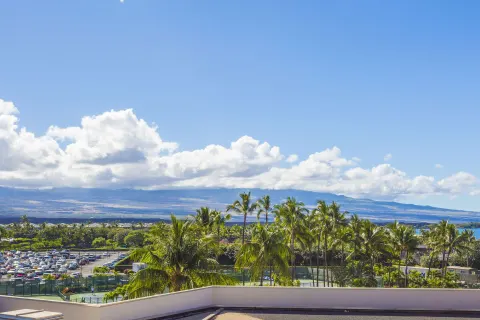 Resort view from Hilton Waikoloa Village with palms, courts, parking, ocean and mountains.