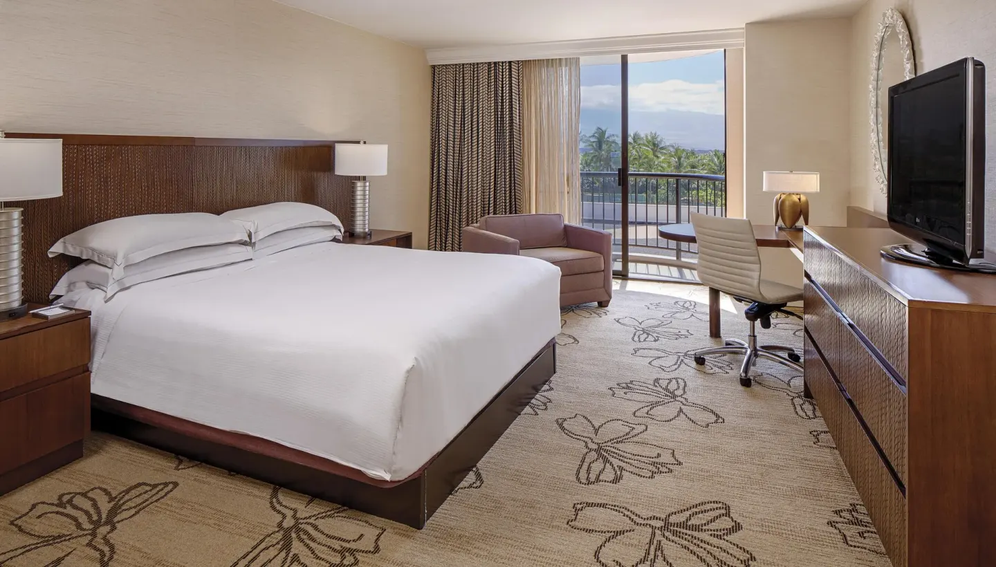 Resort view king room with balcony, desk and TV at Hilton Waikoloa Village.
