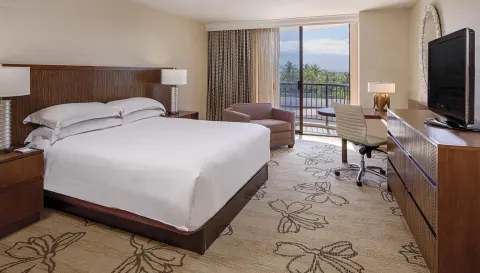 Resort view king room with balcony, desk and TV at Hilton Waikoloa Village.