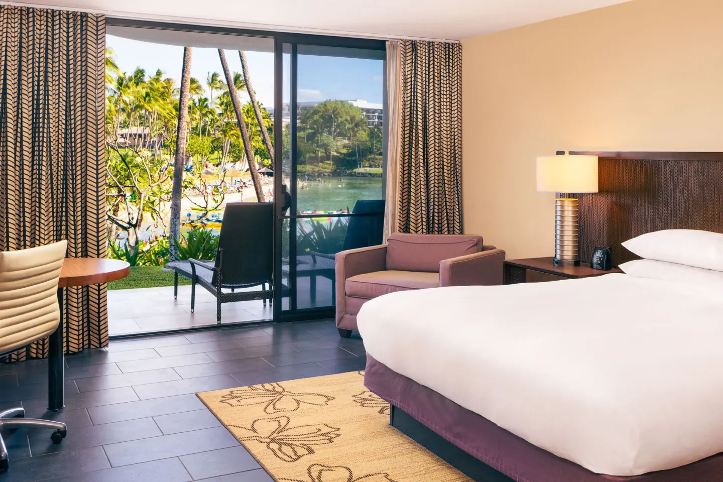 Resort view guest room with king bed and patio at Hilton Waikoloa Village.
