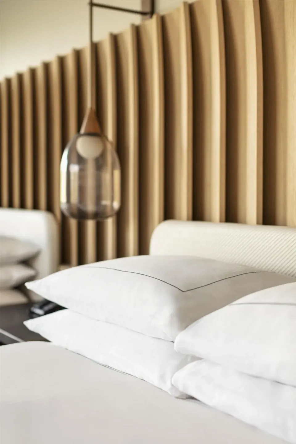 Close-up of pillows, pendant light, and wood headboard in a room at Hilton Waikoloa Village.