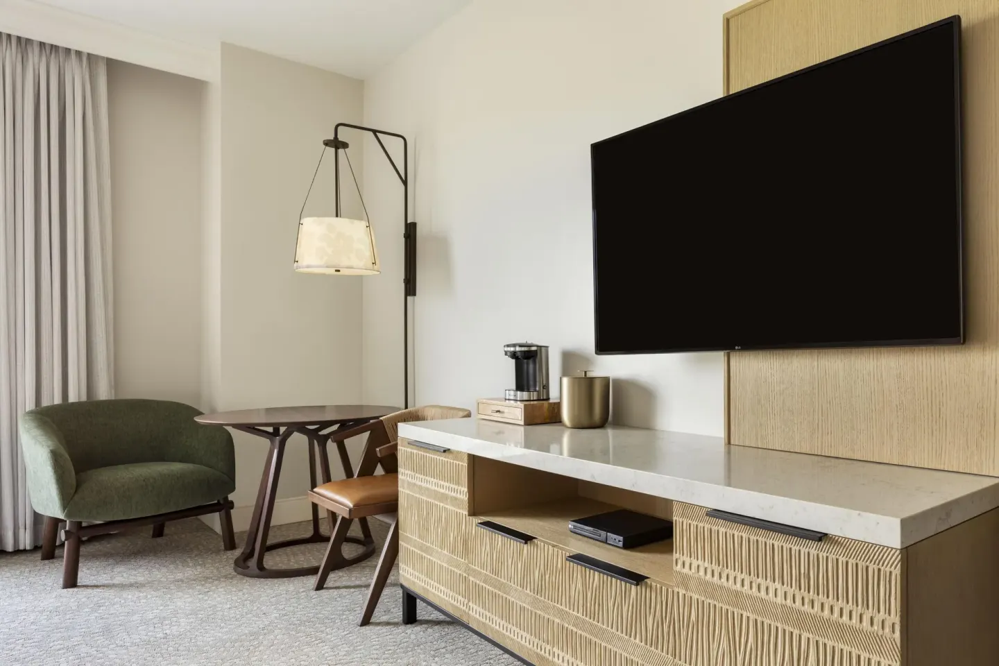 TV console, table, chair, and lounge chair in a guest room at Hilton Waikoloa Village.