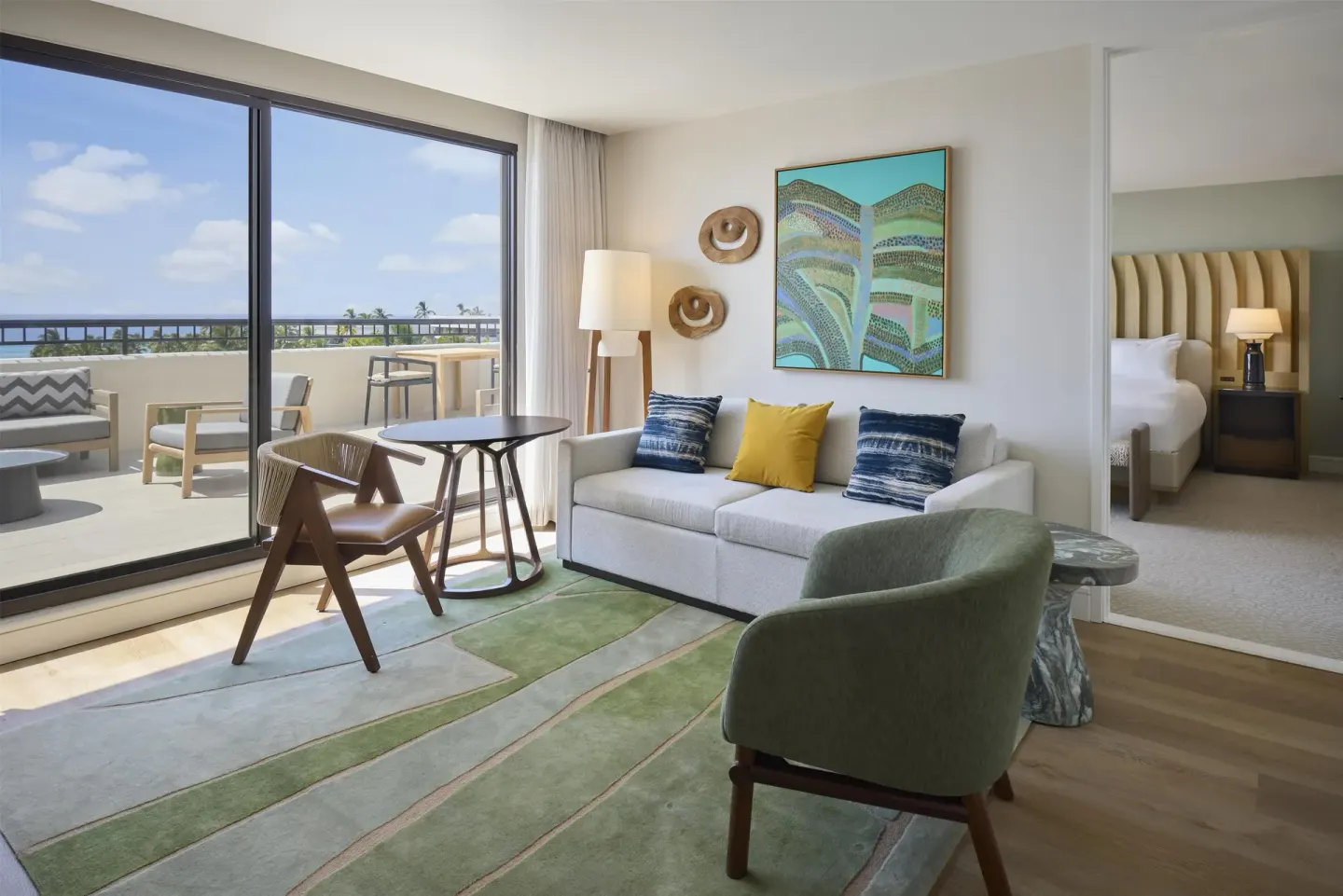 Accessible one-bedroom suite living area with sofa and balcony at Hilton Waikoloa Village.
