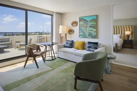 Accessible one-bedroom suite living area with sofa and balcony at Hilton Waikoloa Village.