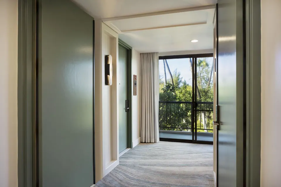 Suite entry hallway with green doors and balcony view at Hilton Waikoloa Village.