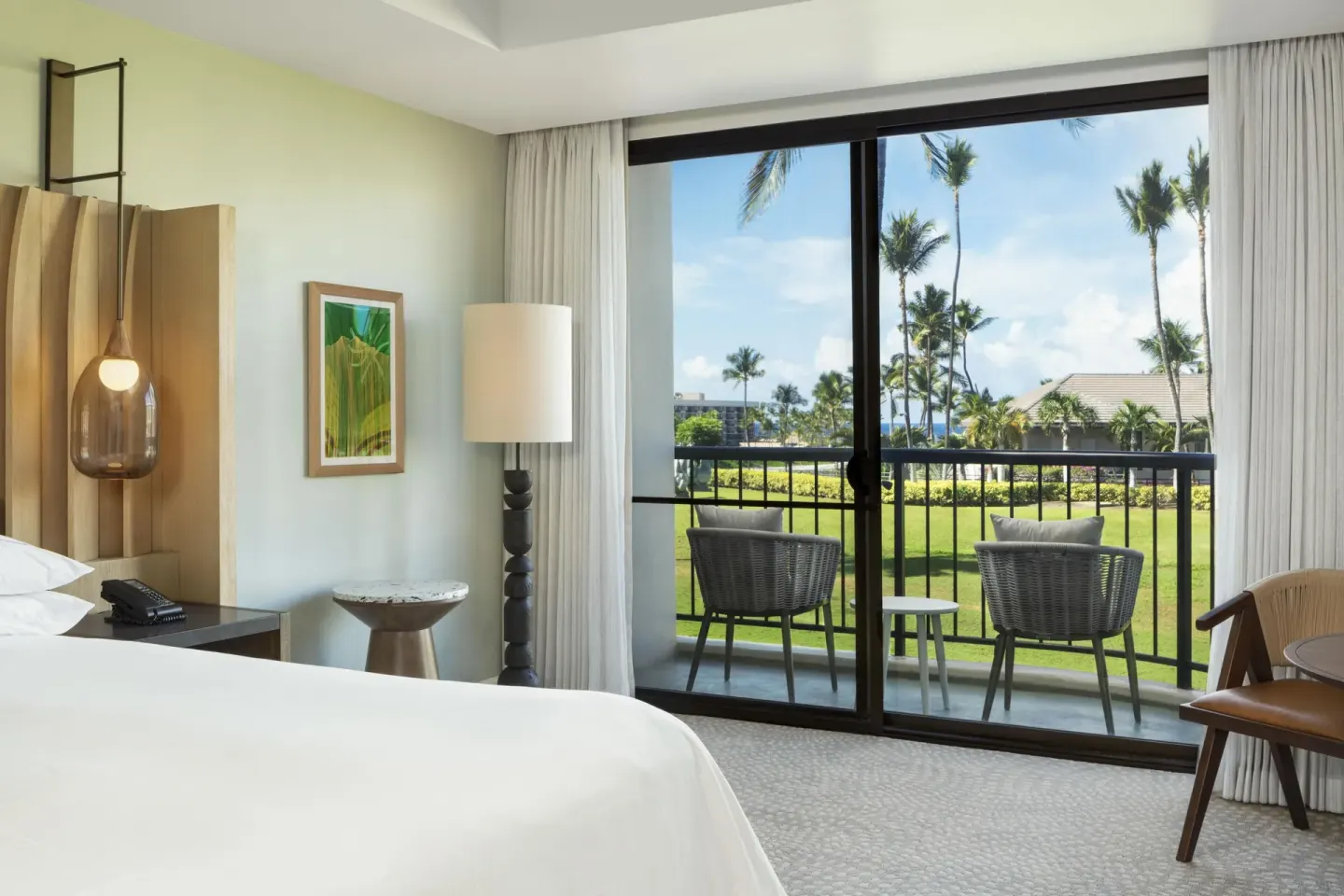 King bedroom detail with balcony chairs and palm views at Hilton Waikoloa Village.