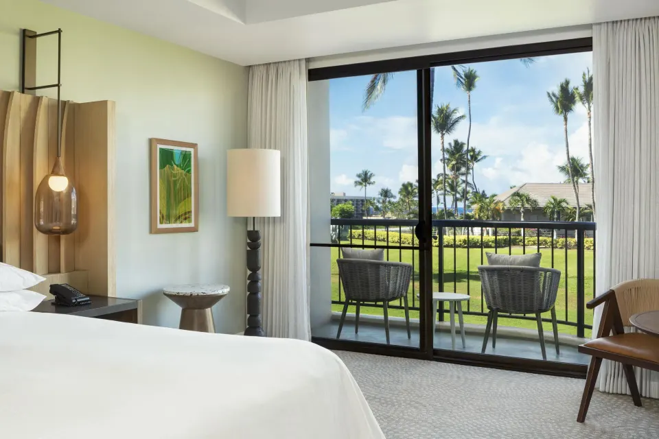 King bedroom detail with balcony chairs and palm views at Hilton Waikoloa Village.