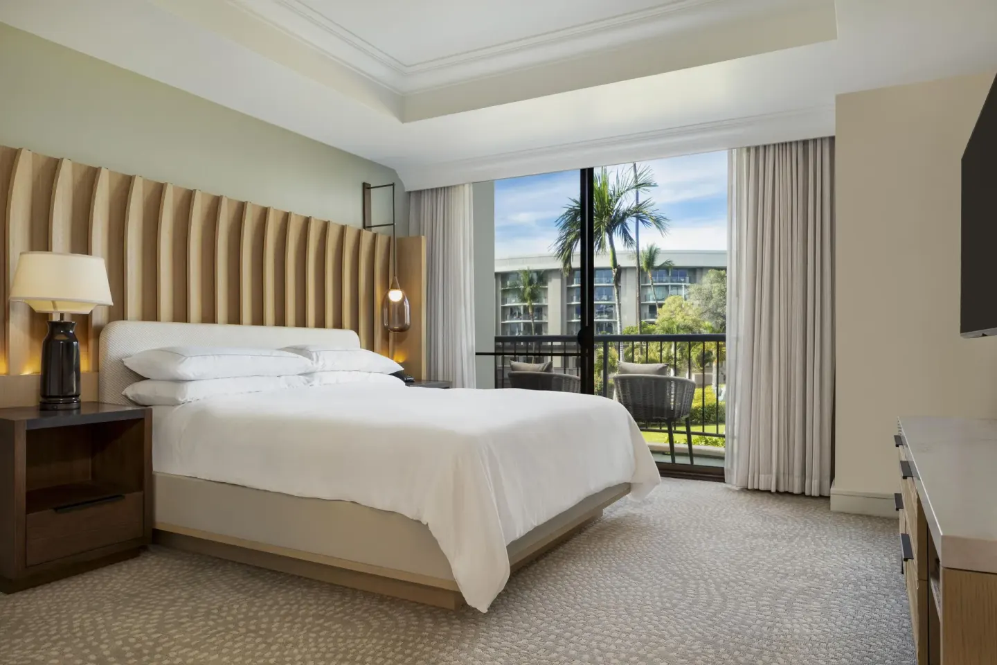 King bed and balcony view in an accessible resort view suite at Hilton Waikoloa Village.