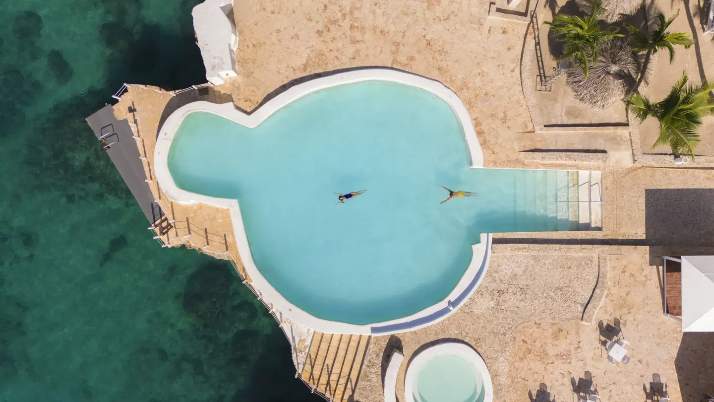 Top-down view of a clover-shaped oceanfront pool at HM Alma de Bayahibe.