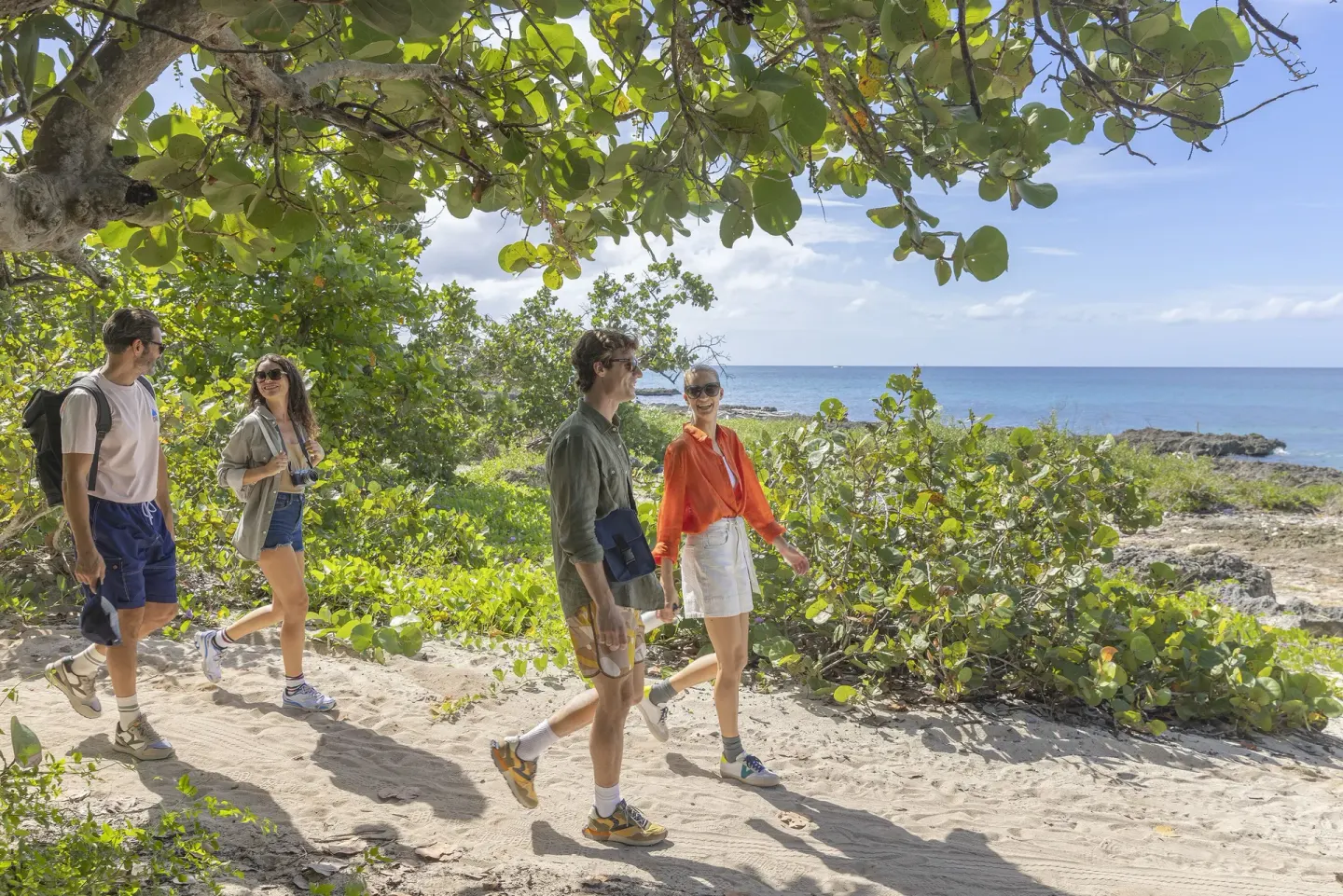 Guests walk a sandy coastal path through greenery at HM Alma de Bayahibe.