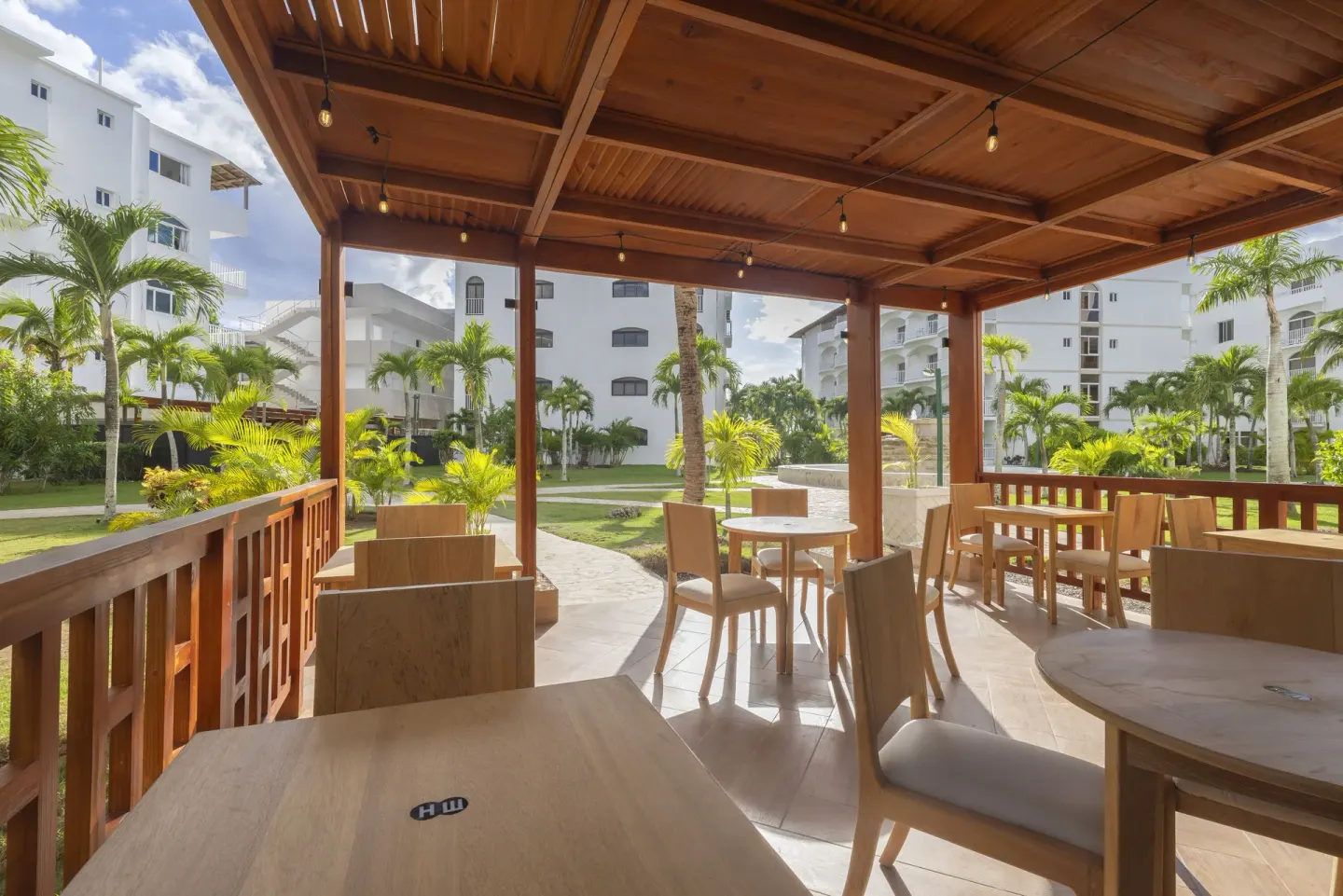 Open-air terrace seating facing palm gardens and white resort buildings at HM Alma de Bayahibe.