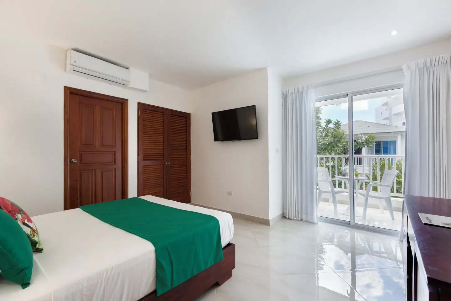 Guest room with king bed, wall TV and balcony doors at HM Alma de Bayahibe.