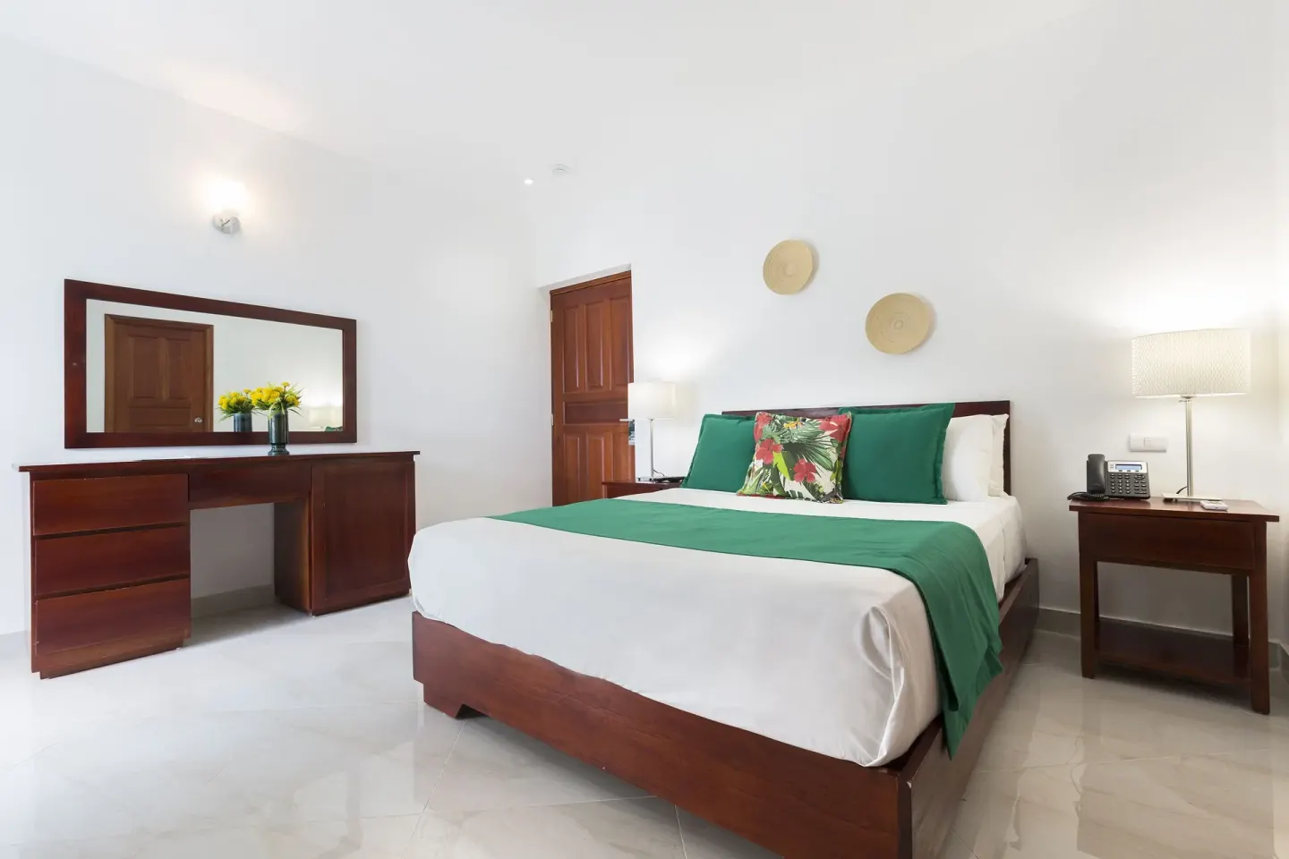 Guest room with king bed, green accents and wood furniture at HM Alma de Bayahibe.