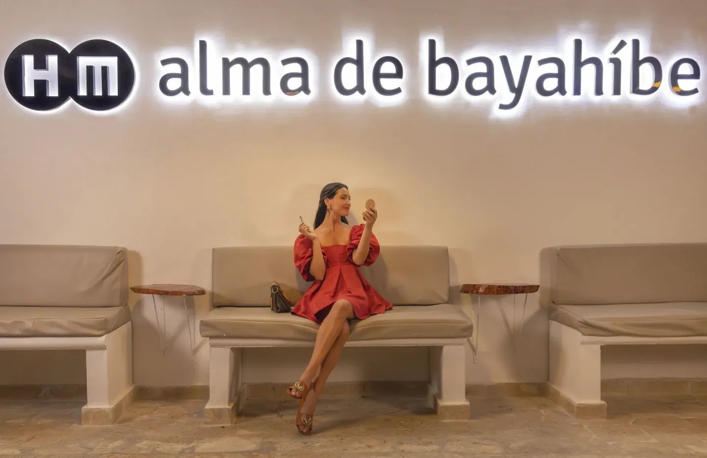 Guest seating beneath the illuminated HM Alma de Bayahibe wall sign.