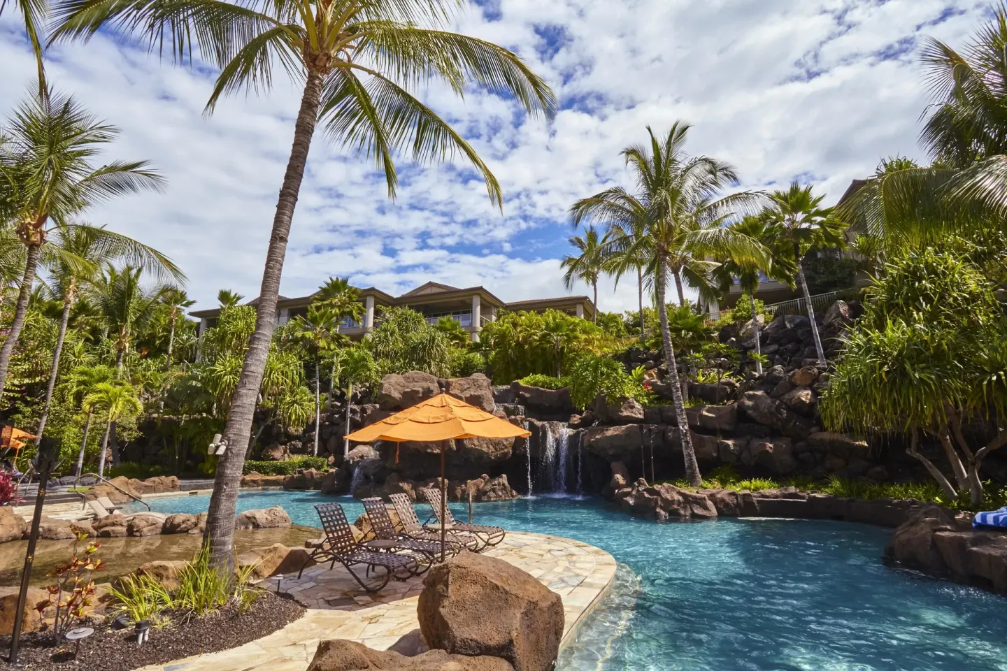 Pool terrace with waterfall, palms, and loungers at Ho‘olei Villas at Grand Wailea.
