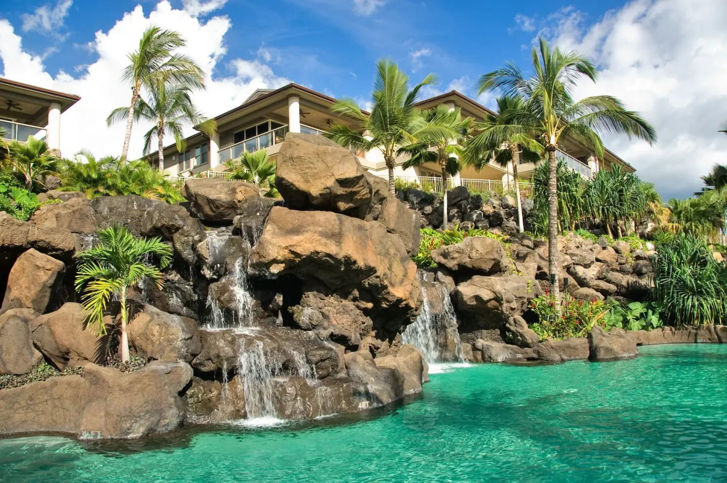 Rock waterfalls flowing into a turquoise pool at Ho‘olei Villas at Grand Wailea.