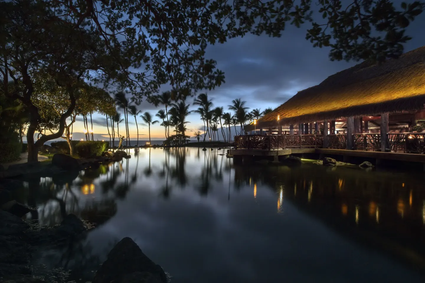 Twilight lagoon and thatched dining pavilion at Ho‘olei Villas at Grand Wailea.