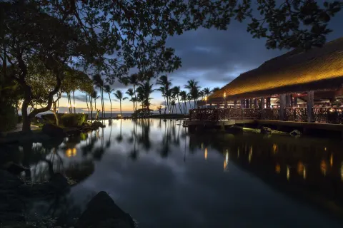 Twilight lagoon and thatched dining pavilion at Ho‘olei Villas at Grand Wailea.