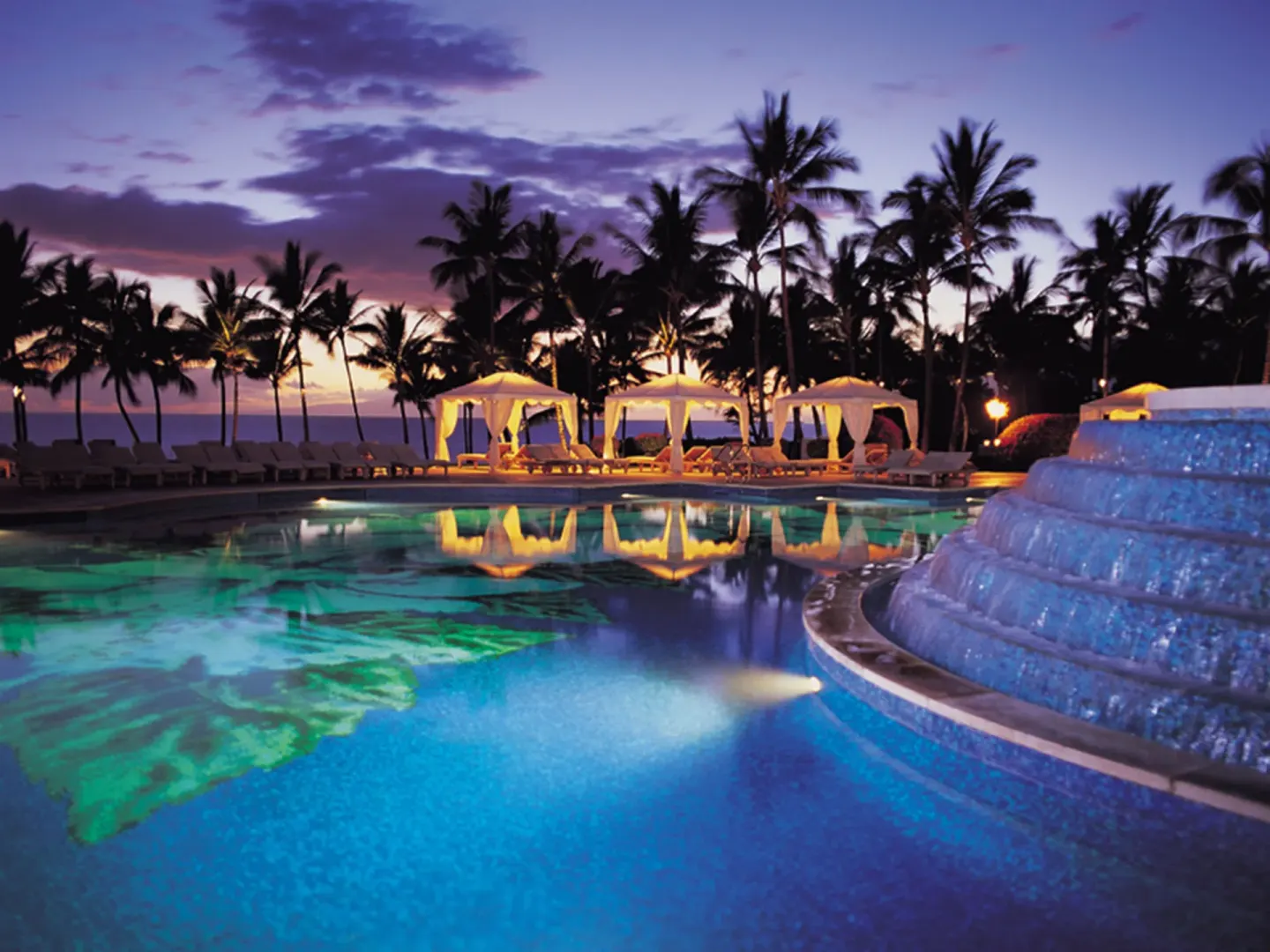 Twilight pool with cabanas and palm silhouettes at Ho‘olei Villas at Grand Wailea.