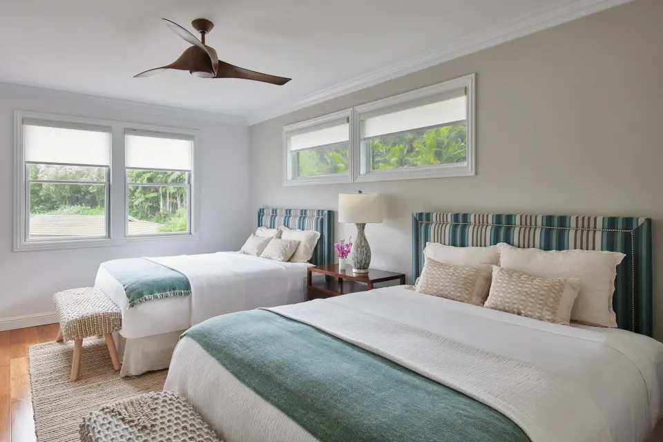 Luxury villa bedroom with two beds, striped headboards, and tropical window views at Ho‘olei Villas at Grand Wailea.