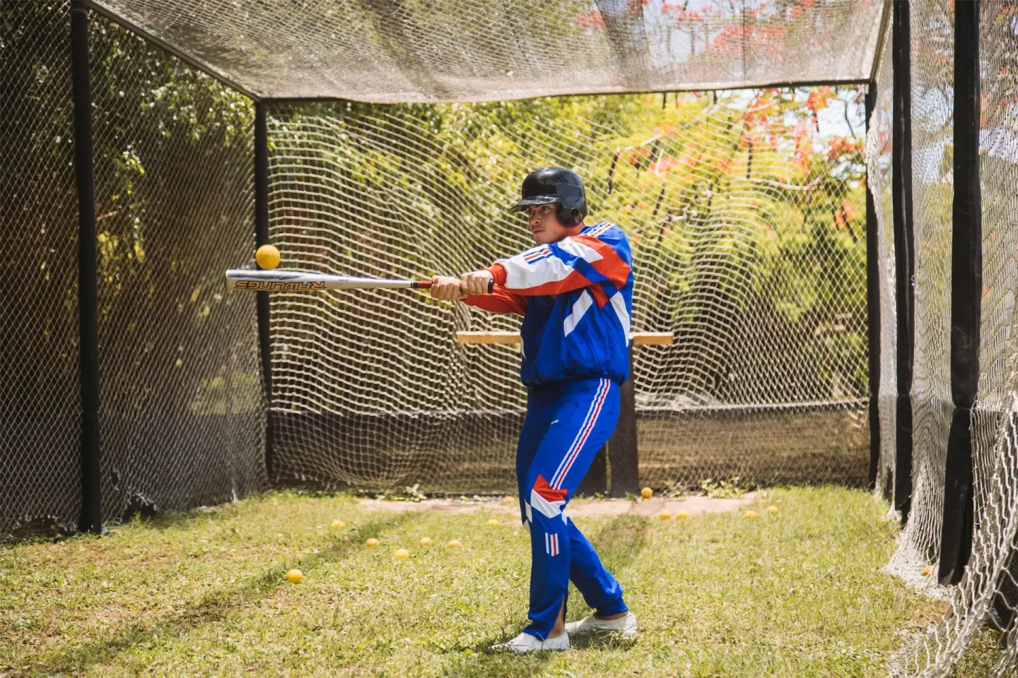 A guest swings a bat in a netted practice cage at Hodelpa Garden Suites Golf & Convention Center.