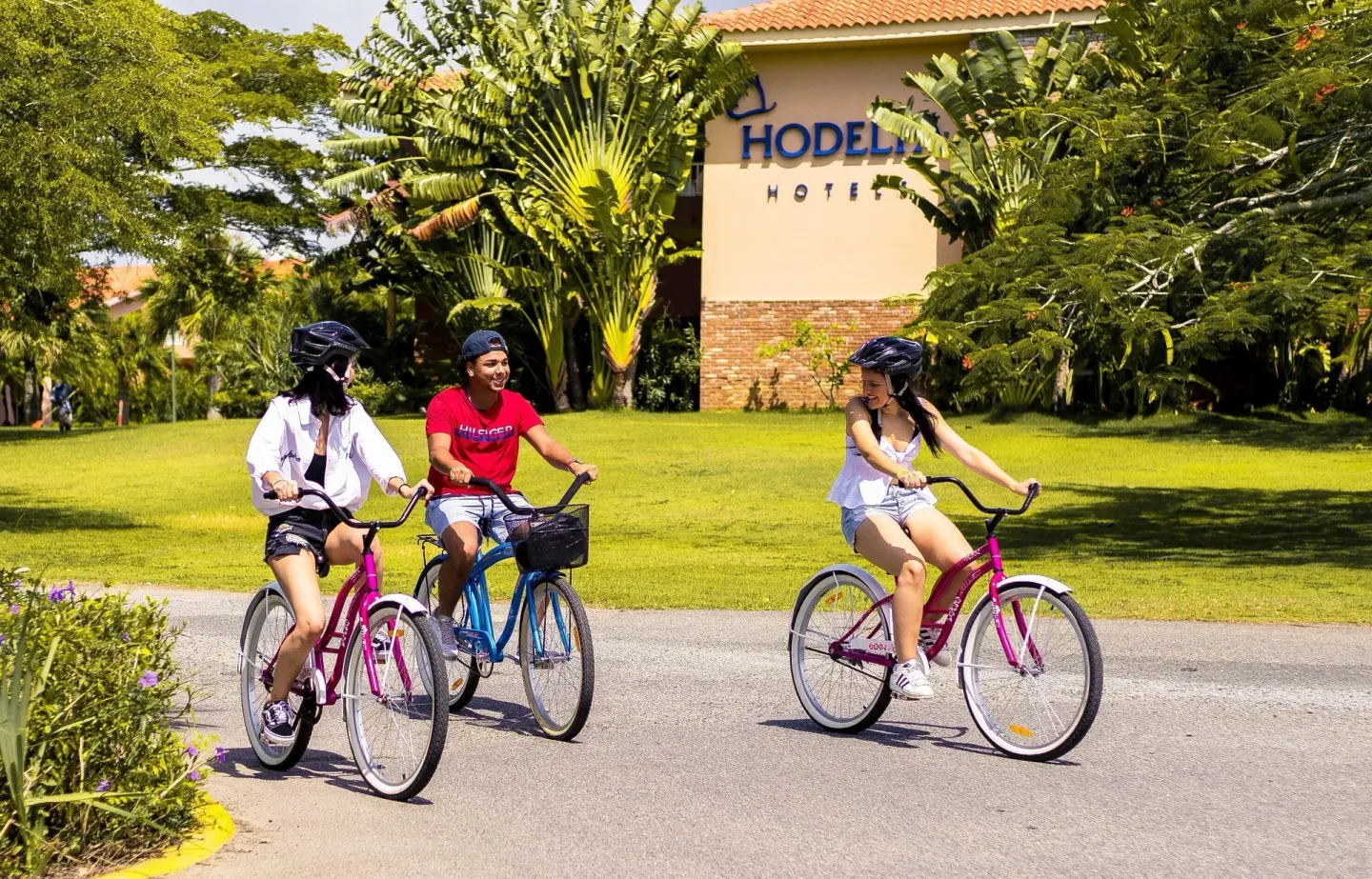 Guests ride bicycles on a resort path at Hodelpa Garden Suites Golf & Convention Center.