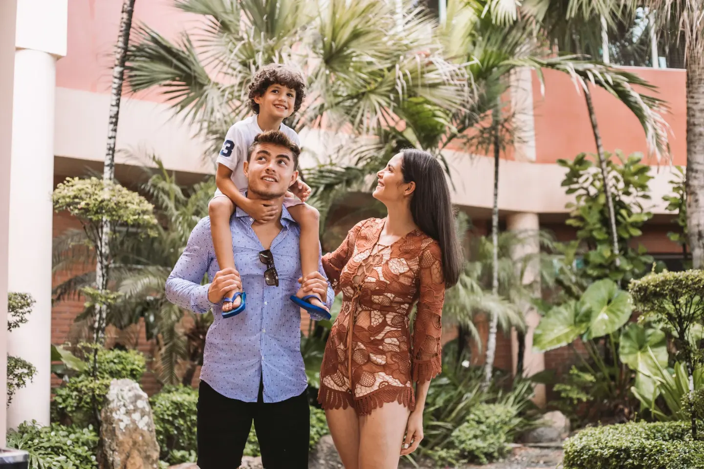 Family walking through tropical gardens at Hodelpa Garden Suites Golf & Convention Center.