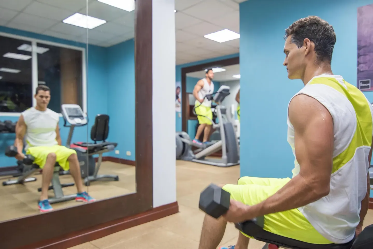 A guest lifts dumbbells in the fitness room at Hodelpa Garden Suites Golf & Convention Center.