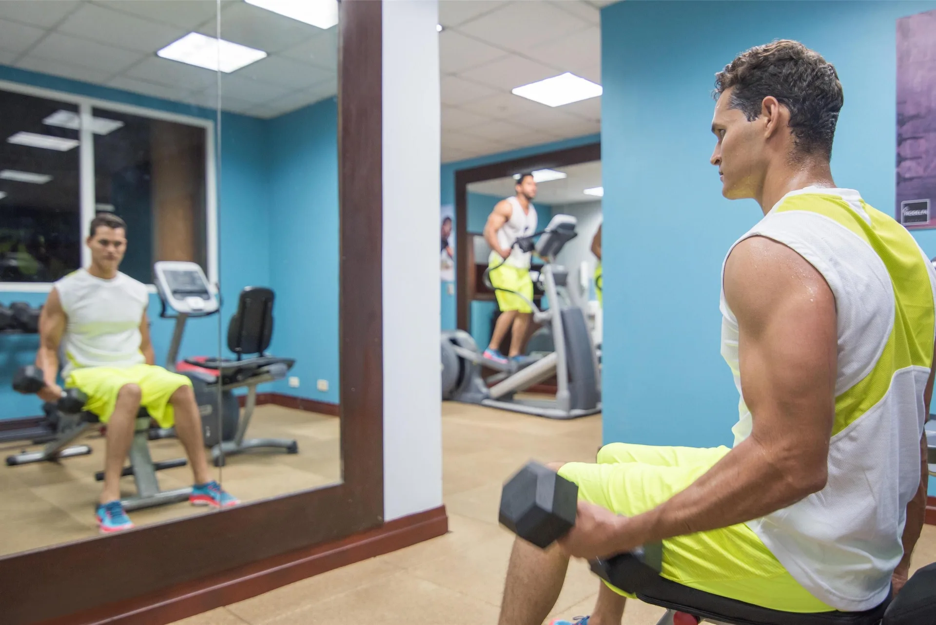 A guest lifts dumbbells in the fitness room at Hodelpa Garden Suites Golf & Convention Center.