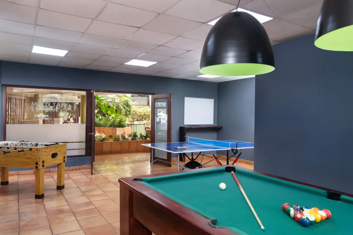 A game room with pool, ping-pong, and foosball at Hodelpa Garden Suites Golf & Convention Center.