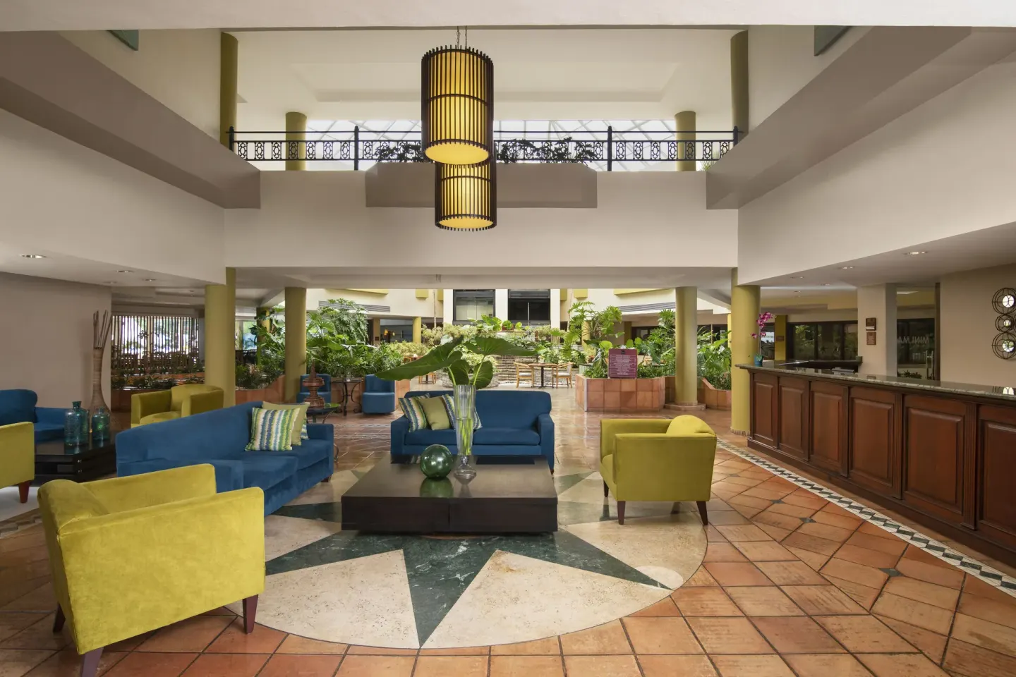 Open-air lobby lounge with blue and yellow seating at Hodelpa Garden Suites Golf & Convention Center.